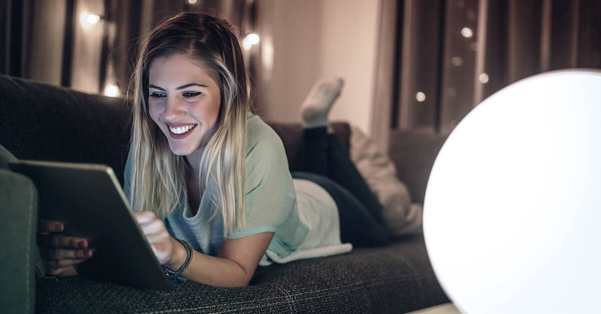 happy lady using a digital tablet on the couch